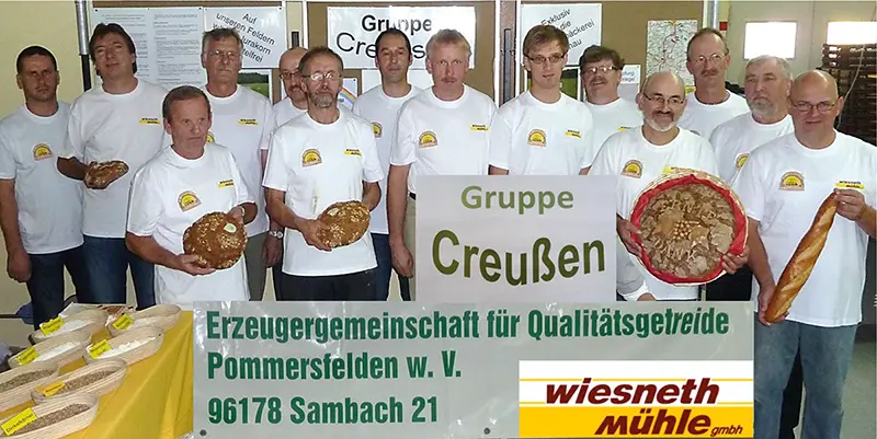 Gruppenfoto der Erzeugergemeinschaft Creußen mit 14 Personen, die zum Teil Brote und Teilchen in der Hand halten