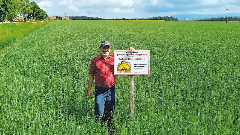 Herr Manfred Stock auf einem seiner Getreidefelder mit Feldtafel