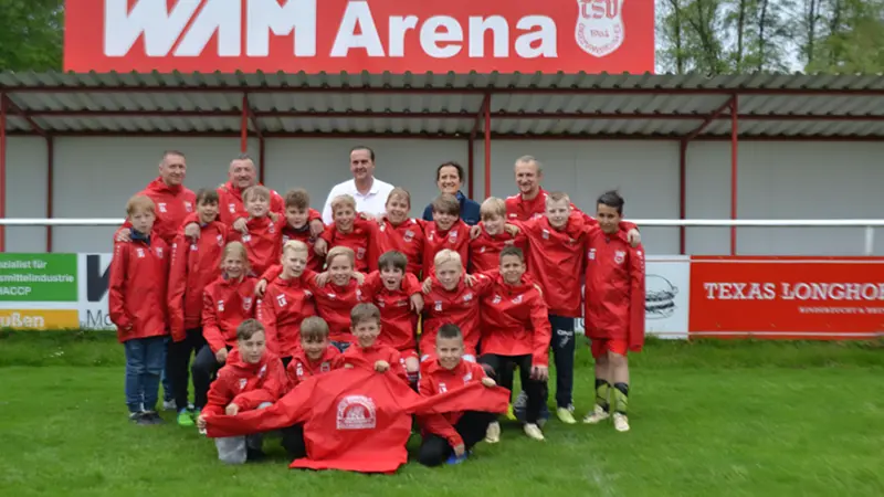 Mannschaftsbild von Jungen in Fußballtrikots zusammen mit mehreren Erwachsenen