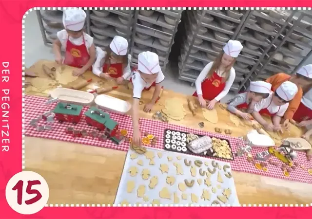 Kinder backen an großem Tisch Weihnachtsplätzchen